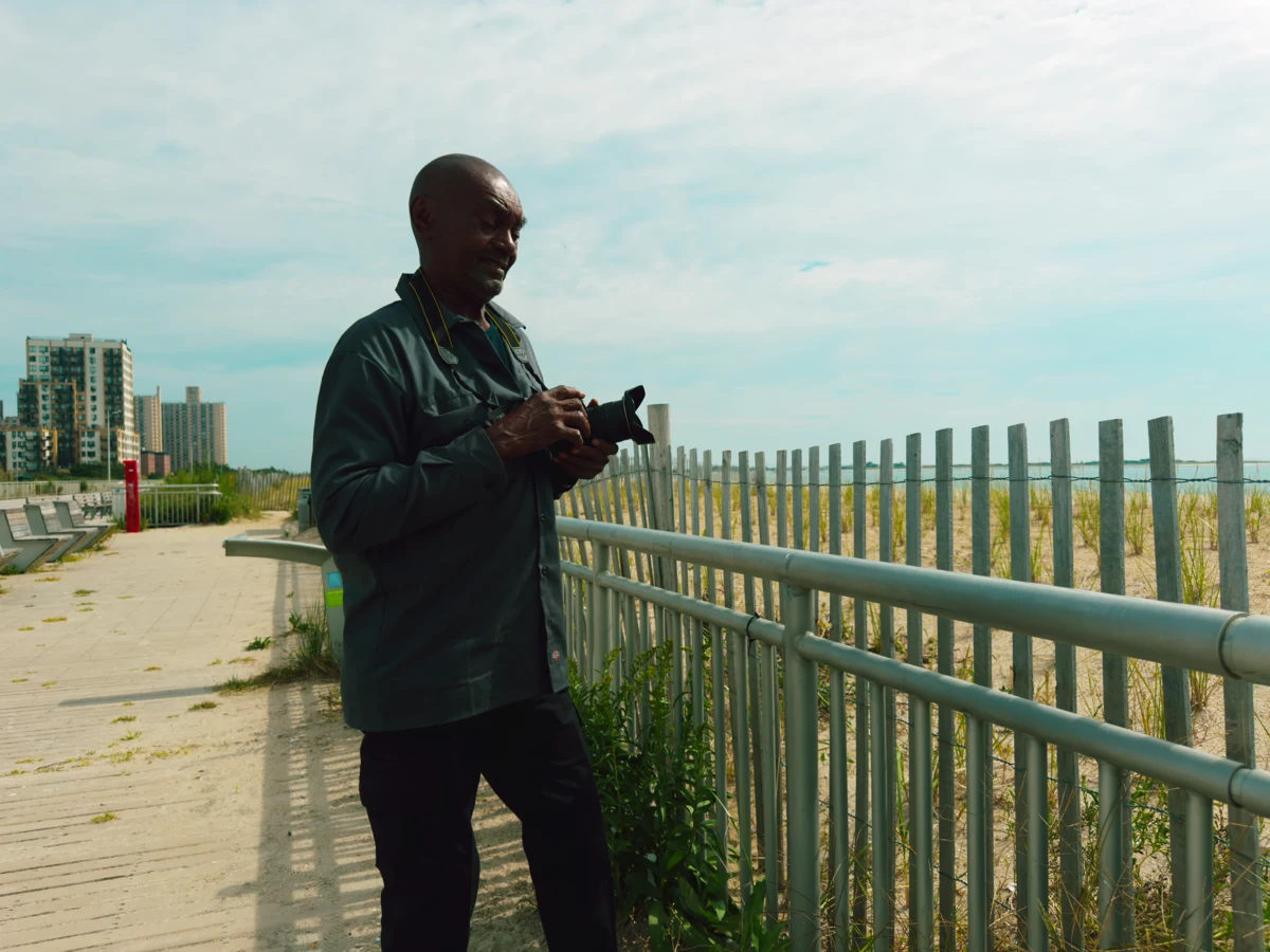 Kenny Harris holding his camera on the boardwalk beside the beach
